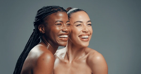 Happy friends with glowing skin in studio light